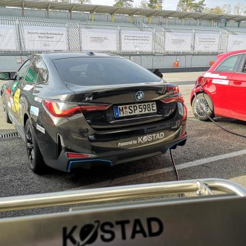Im Vordergrund der Kostad-Schriftzug, im Hintergrund ein BMW i4, der gerade geladen wird.