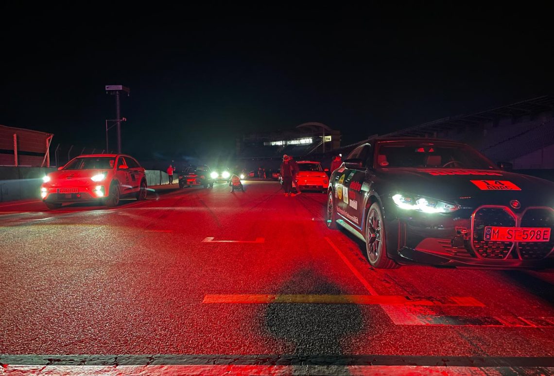 Startaufstellung verschiedener Elektroautos bei Nacht. Alles ist rot beleuchtet.