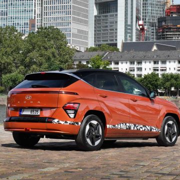 Hyundai Kona Elektro in orange von schräg hinten.