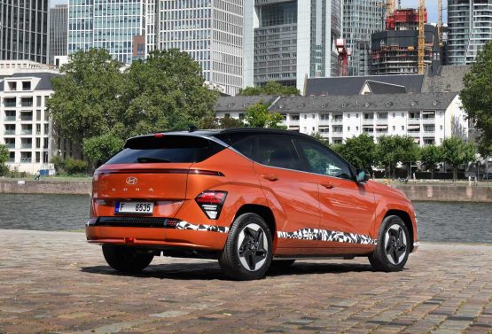 Hyundai Kona Elektro in orange von schräg hinten.