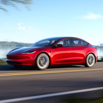Tesla Model 3 Highland in Ultra Red von schräg vorne bei der Fahrt.