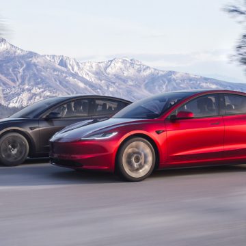 Tesla Model 3 Highland in Ultra Red und Stealth Grey von schräg vorne bei der Fahrt.