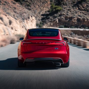 Tesla Model 3 Performance in Ultra Red von hinten bei der Fahrt