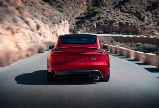 Tesla Model 3 Performance in Ultra Red von hinten bei der Fahrt
